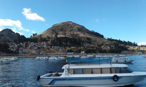 Boats moored in sea against blue sky