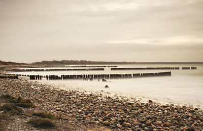 Moody sunset over the sea beach. foamy water level donne by big waves strike into old breakwater