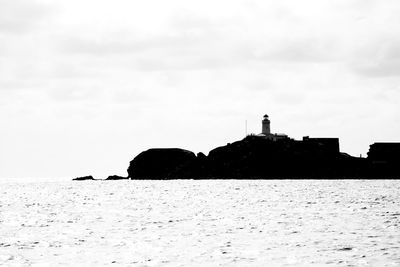 Lighthouse by sea against sky