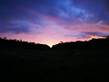 Silhouette landscape against dramatic sky during sunset
