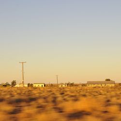 Electricity pylon on field against clear sky during sunset