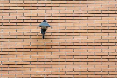 Low angle view of street light on brick wall