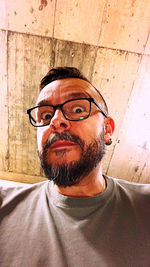 Portrait of young man wearing eyeglasses against wall