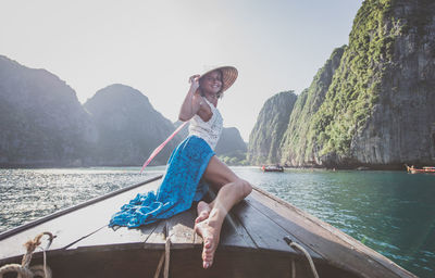 Man sitting on boat in sea against sky