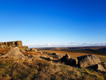 Scenic view of rocks on field against blue sky