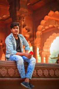 Full length portrait of young man sitting outdoors