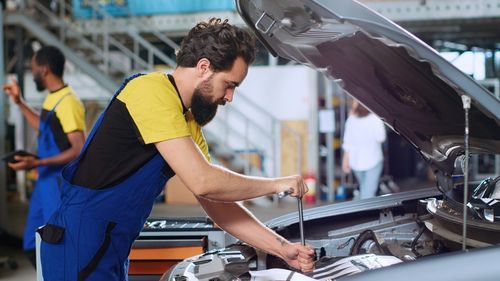 Rear view of man repairing car