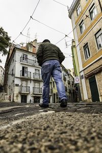 Rear view of man on street against buildings in city