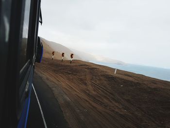 Scenic view of road by sea against sky