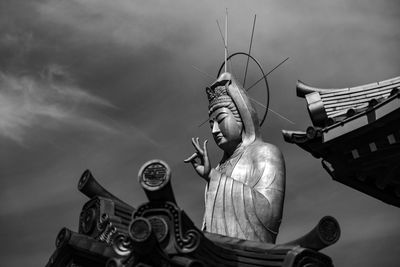 Low angle view of a giant, buddhist statue standing against sky.