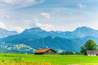 House on field by mountains against sky