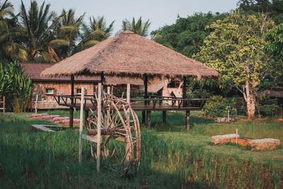 Traditional house on field against trees and houses