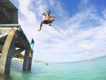 Man jumping in sea against sky