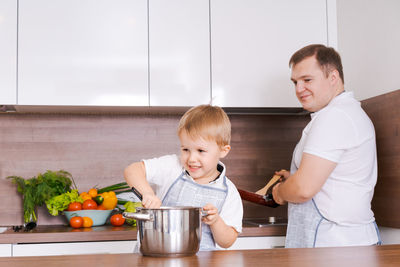 Family cooking in household dad with son, cook dinner for mom, have fun