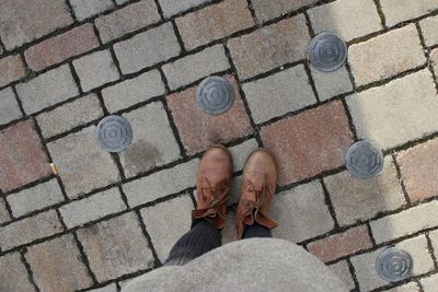 Low section of woman standing on cobblestone street