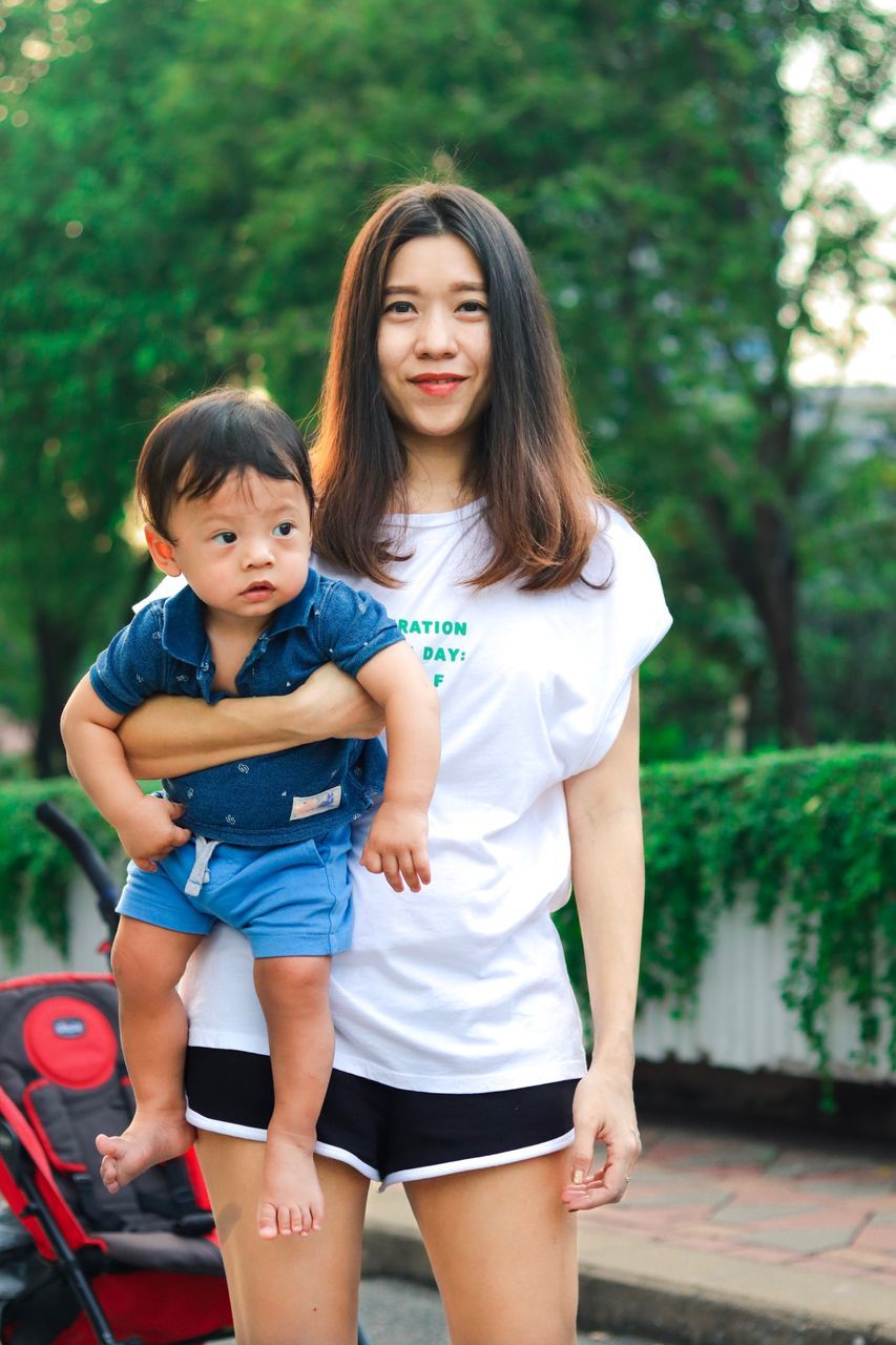 child, childhood, looking at camera, real people, portrait, females, two people, women, togetherness, family, three quarter length, focus on foreground, innocence, day, standing, males, people, hairstyle, outdoors