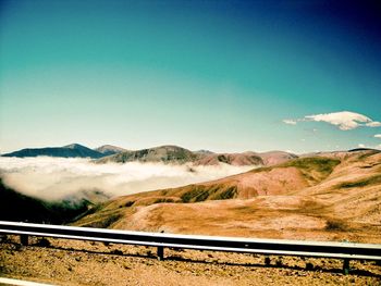 Scenic view of road by mountains against sky