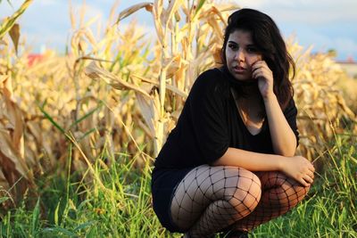 Young woman crouching on grassy field