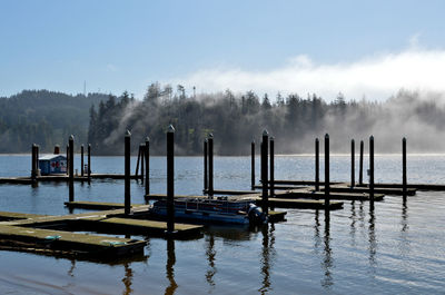 Wooden posts in lake against sky