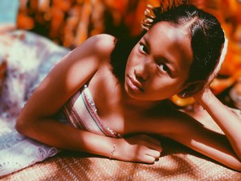 Portrait of young woman lying down on bed