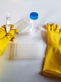 Close-up of hand holding yellow paper over white background