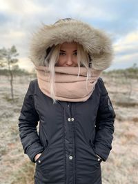 Portrait of young woman wearing warm clothing while standing on land against sky