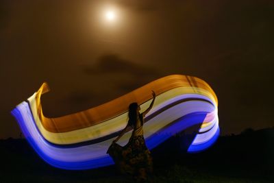 Person standing on illuminated stage against sky at night