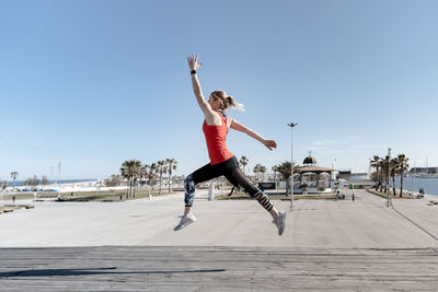 Woman jumping in mid-air against sky