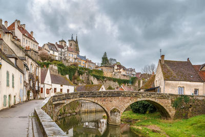 Arch bridge over buildings against sky