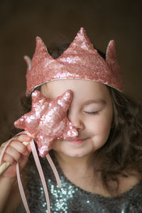 Close-up of girl holding magic wand while wearing crown