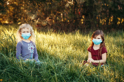 Friends wearing masks while sitting on grass