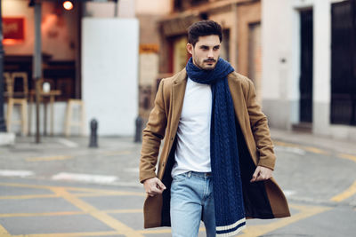 Handsome young man walking on street in city