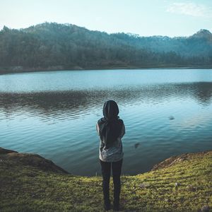 Rear view of woman standing by lake