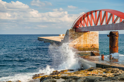 Sea waves splashing on rocks against sky