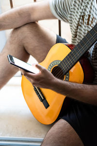 Midsection of man playing guitar