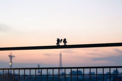 Silhouette people on bridge against sky during sunset