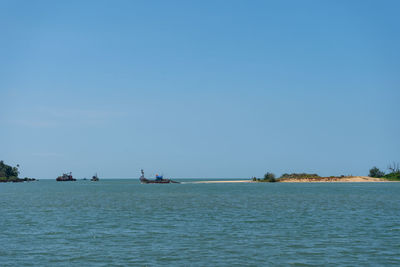 Sailboats sailing in sea against clear sky