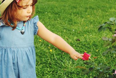 Girl touching rose while standing on field
