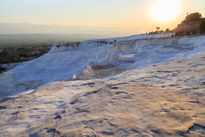 Scenic view of frozen landscape against sky during sunset