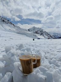 Coffee cup and ice cream against sky during winter
