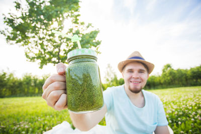 Portrait of man holding jar against plants