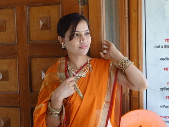 Woman in sari looking away while standing against door