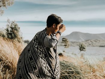 Side view of young man on land against sea