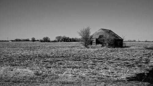 Abandoned barn on field against clear sky