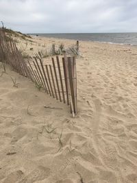 Deck chairs on beach against sky