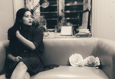 Thoughtful woman sitting on sofa at home