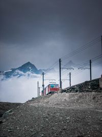 Low angle view of train on mountain against cloudy sky