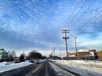 Road passing through city against cloudy sky