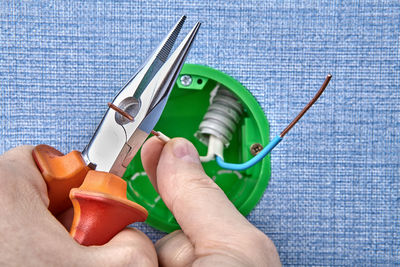 Cropped hands cutting wire of electrical outlet