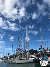 Sailboats moored at harbor against sky